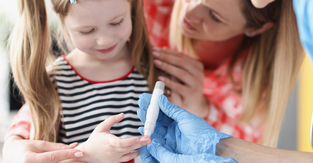 medical staff helping young girl check blood sugar levels
