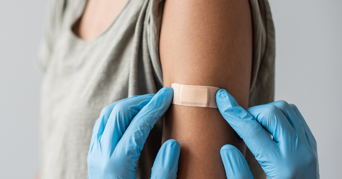 Someone having a bandaid placed on their arm after an immunization.