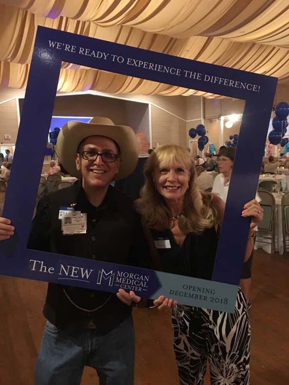 Sarah Burbach and another employee smiling and holding up an Instagram prop celebrating the opening of the new Morgan Medical Center.